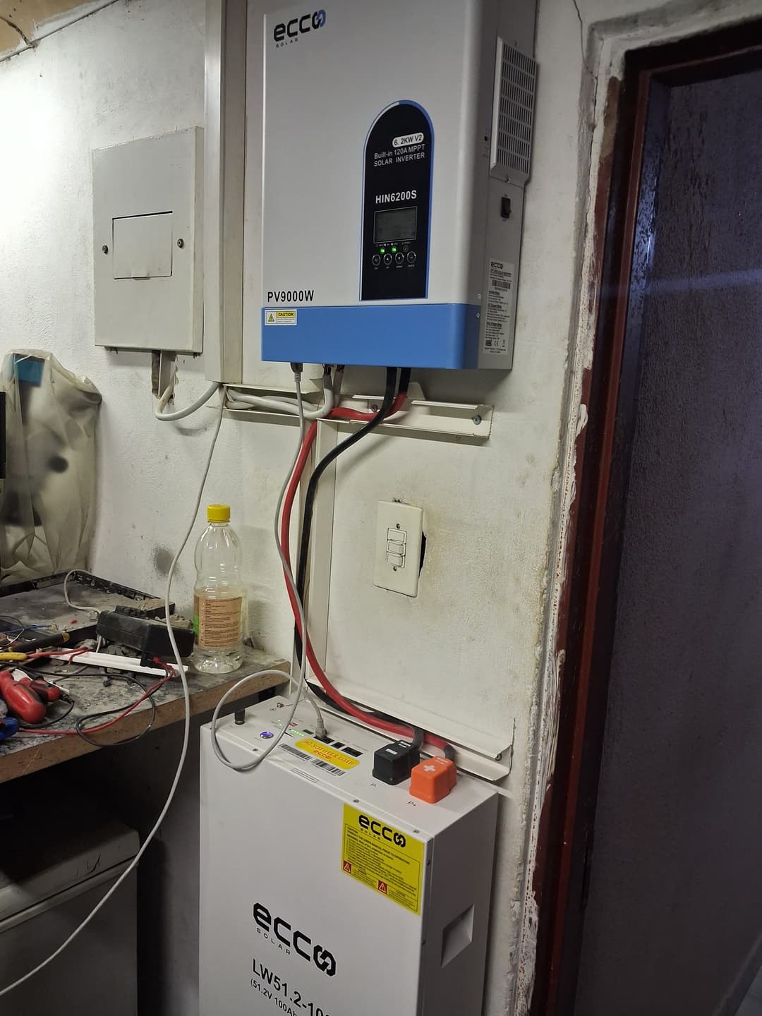 Modern hybrid inverter and lithium-ion battery bank installed on a garage wall